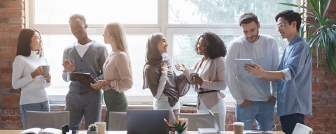 A diverse group of people standing and talking in a meeting room