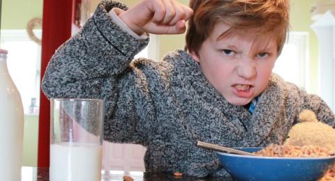 upset boy at breakfast table