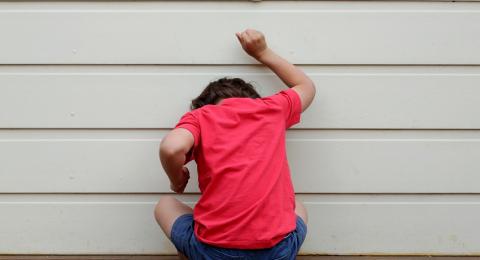 child sitting on floor knocking on wall