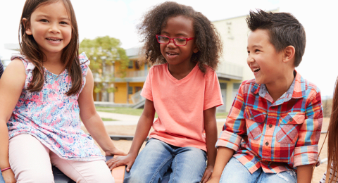 A group of children smiling while sitting on playground equipment