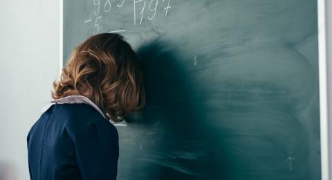 child with head resting against chalkboard