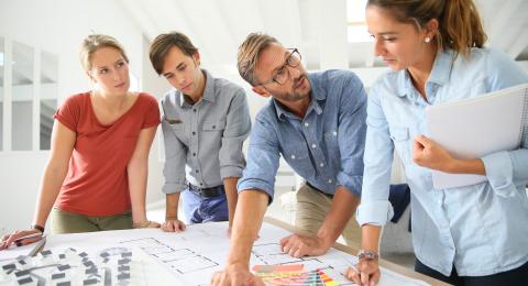 people standing around architectural drawing