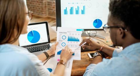 man and woman sitting at desk analyzing data