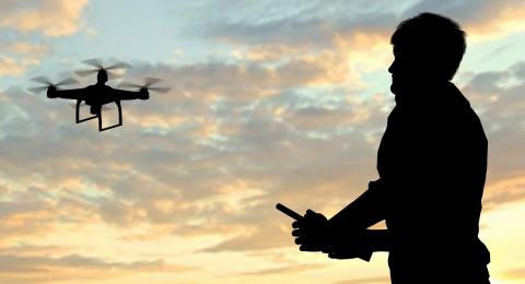 man flying drone at sunset