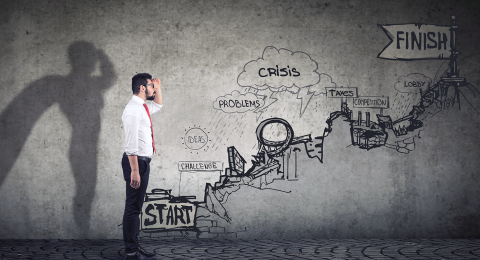 Photo illustration of a business man next to a wall with drawing of a difficult business climb