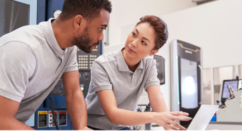 man and woman having discussion while leaning over a laptop