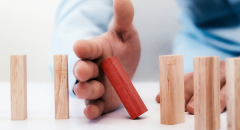 man toppling wooden blocks