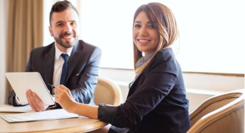 Two smiling professionals reviewing paperwork