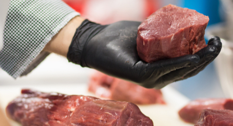 black-gloved hand holding cut of beef