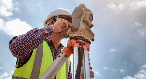 Surveyor using telescope at construction site