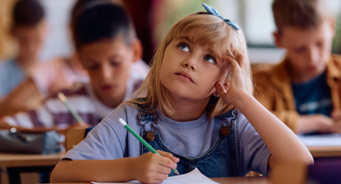 Pensive schoolgirl writing a test 