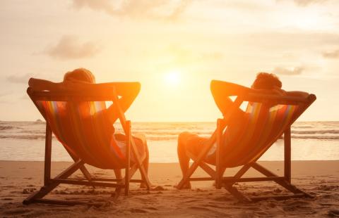 Two people relaxing on chairs on the beach during sunset