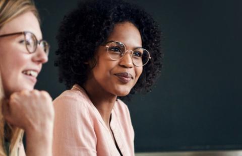 Two women with glasses sitting and smiling