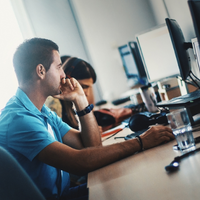 Two students at monitors coding