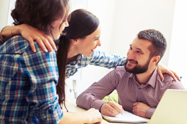 Three smiling people huddling at a table