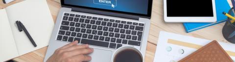 Overhead of someone's hands working on a laptop keyboard in an office