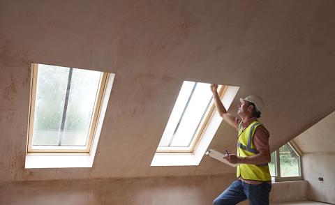 Home inspector in a yellow construction vest examining a window