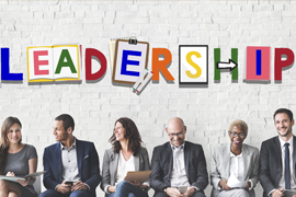 Businesspeople in chairs against a wall with the word "Leadership" above them