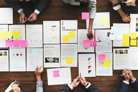 overhead of a table with people working on pages and sticky notes