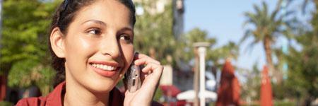 Smiling person on a phone outdoors with palm trees in the background