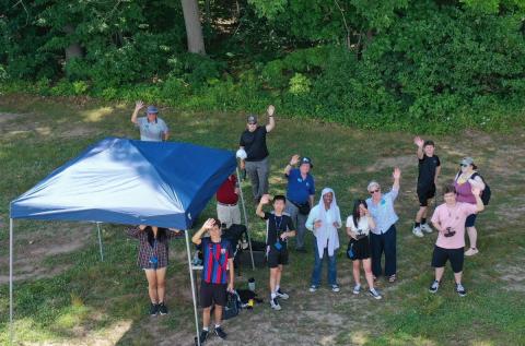 Upward Bound group on the ground waving upward to the drone taking the photo