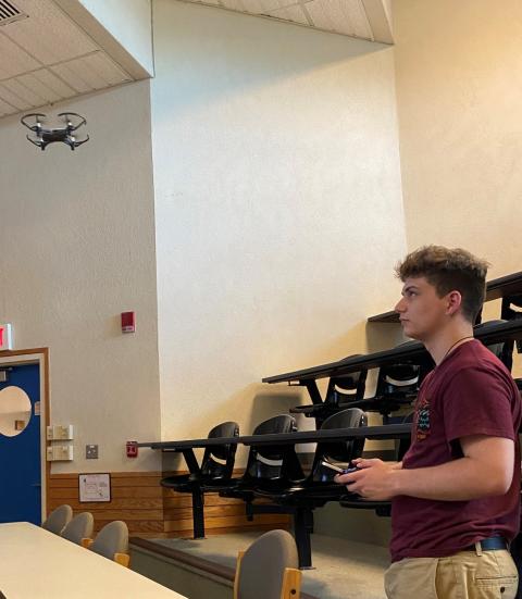 Upward Bound student flying a drone inside a lecture hall