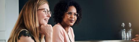 Two women with glasses sitting and smiling