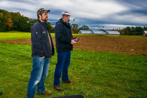 Two people controlling drone in field