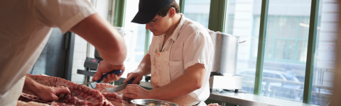 two workers cutting meat