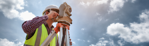 Surveyor using telescope at construction site
