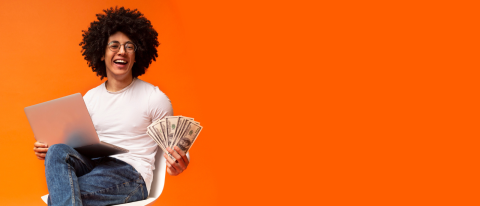 happy person holding money and laptop