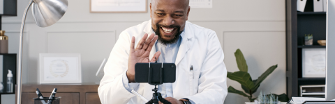male doctor waving at virtual patient on cell phone