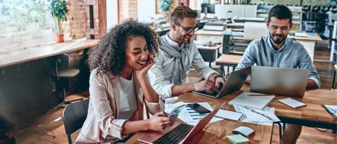 three coworkers smiling at computers