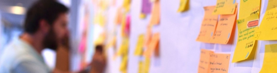 Man placing post it notes on wall using Agile-Scrum methodology